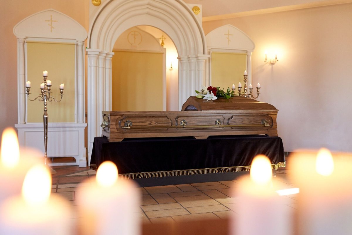 Camera ardente allestita con candele accese e cofano funebre